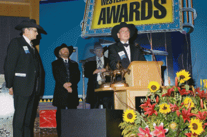 Giving acceptance remarks at the Western Heritage Awards, surrounded by John R. Erickson, Michael Martin Murphey, and Waddie Mitchell Photo by Joe Ownbey.